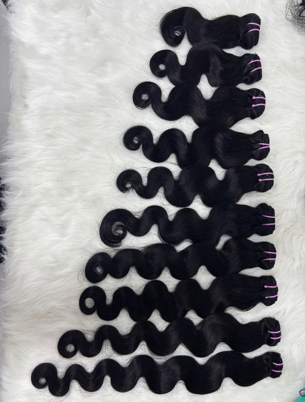 100% raw Vietnamese body wave hair bundles in natural black arranged by length on a white fur background, Grade 12A
