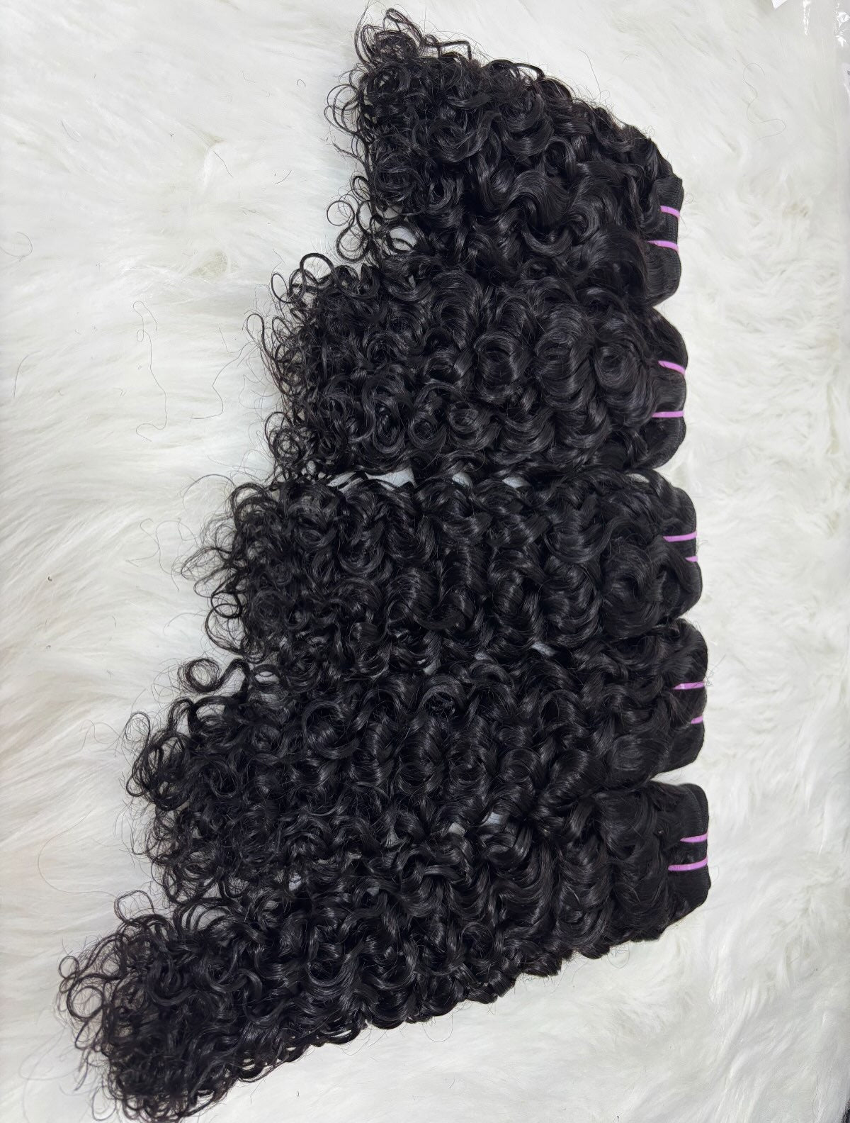 100% raw Vietnamese water wave hair bundles in natural black showing tight springy waves and weft ties, Grade 12A
